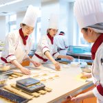 人材不足と機械化が加速する飲食業界は、若者にとって大きなチャンスの時代へ! 大手・個人店で二極化する飲食業界「好き」を仕事にした先の未来とは? ツイート シェア はてブ 送る 調理現場の機械化が進む調理・製菓業界では、求められる資質も変化している。単純作業は機械に任せて、人間はより想像力を駆使した仕事に取り組む必要があるという。人材不足が加速するなか、調理師やパティシエを目指す若者の活躍の場はますます広がっている。東京・横浜に2校を運営する学校法人誠心学園の広瀬道理事長に話を伺った。 必要なのは変化する調理・製菓の現場で何をすべきか「想像する力」 一流ホテルや高級店に就職できるチャンスが拡大 ―慢性的な人材不足やインバウンド需要が話題の飲食業界の現状をどうご覧になっていますか? 食料品の小売業を含むフードビジネスの従業員数は、800万人を超える規模で、日本の就業人口の1割以上を占める一大市場です。それだけに人材不足は深刻で、近年は外国人労働者の増加が顕著です。特に牛丼チェーン店など飲食大手企業での外国人雇用が拡大しています。 飲食業界の中小企業では、跡継ぎ問題が深刻化しており、人気を維持している「名店」でも閉店を余儀なくされるケースが増加しています。これは地方においてより顕著です。人材不足以外に材料費の高騰も飲食業界の大きな経営課題となっています。製菓の分野では、いちごショートケーキ1ピースが800円超えという時代に突入しています。 明るい話題としては、インバウンド需要は引き続き活況です。個人的には現在の年間4000万人規模ではまだ少ないと思っていて、日本の観光立国としてのポテンシャルはまだ十分に発揮されていないと思います。訪日外国人旅行者が増加すれば、ホテルのレストランなど、飲食業界の求人もさらに増えるでしょう。 人材不足の課題は、学生にとっては希望となります。以前は高いハードルとされていた一流ホテルや高級店への就職も夢ではありません。売り手市場のため、飲食業界で働く若年層の転職も盛んです。早期離職を防ぐため、老舗料亭などでも1年目から焼き物や刺身など多様な業務を経験させる方向に変化しています。従来10年かけて習得していた技術を4〜5年で身につけられるよう、教育システムが変革されているのが現状になります。 ―飲食業界の新時代において、調理・製菓の専門学校ではどのような学びを提供しているのでしょう? 先ほども申し上げた通り、調理現場の機械化は加速するでしょう。このAI時代の人材育成において、重要になるのは、「想像力」です。定型的な業務はAIでも対応可能になるため、人間にしかできない「想像する力」「考える力」の育成が急務とされています。調理実習においても、単純な技術の習得だけではなく、理論的理解を深める教育への転換が求められていると思います。 専門学校は、「クッキングスクールの延長」ではいけない。真の職業教育を提供するには、各分野の理論と実践を組み合わせた体系的なカリキュラムが不可欠です。個別の技術を身につけるだけでなく、各料理の全体像を理論的に理解できるような教育が求められているのです。 例えば、誠心学園が運営に携わる東京誠心調理師専門学校では、入学してから飲食業界で働くための幅広い体験ができるカリキュラムを用意しています。2年制コースの場合、1年次に和・洋・中の調理の基礎技術・理論を身につけた後、2年次は1年間を4クールに分けて、フレンチ、イタリアン、日本料理の実習を学生自身が選ぶことができます。 製菓の学びについては、横浜にある国際フード製菓専門学校のコースがいいサンプルになります。2年制の製菓製パン科では、1年次に洋菓子・和菓子・パンの基礎技術・理論を学び、2年次はこの3種から1コースを選び、実習を通して、専門的に学びます。いずれも体系的な理論を理解した上で、専門技術の習得という流れになっています。 卒業時に取得できる資格もしっかり確認しておこう ―調理・製菓の専門学校を選ぶ際のポイントはありますか? これは私の持論でもありますが、校舎の設備を見れば、その専門学校のコンセプトがわかります。設備には、その学校の意向が強く反映されています。最近は校内にレストランを併設し、実習型の授業などで活用する専門学校も増えています。最新鋭の調理器具にこだわる学校もあれば、大規模な調理機器を配備している学校もあります。ここからどのような調理師や製菓衛生師を養成したいかが見えてきます。 卒業時に取得できる資格もしっかり確認しておきましょう。専門学校を卒業すれば、「調理師免許」「製菓衛生師」「菓子製造技能士」などの国家資格を取得できると思われがちですが、学校によってはコースを修了しても資格を取得できないケースがあるので注意が必要です。 ―調理・製菓の専門学校卒業後はどのような会社に就職できますか? 調理師専門学校の卒業生の就職先は、一流ホテルや一等地に立つレストラン、機内食や海外日本大使館などが挙げられます。製菓専門学校の卒業生は、一流ホテルの製菓部門や有名チェーン店のほか、専門店に就職してパティシエとして活躍する道が拓けます。しっかり技術と知識を身につければ、憧れの有名店で働けるチャンスは広がっています。 専門学校を選ぶ際は、卒業生の就職先を確認すべきです。学校によって、特定の業界や地域との強いネットワークがある場合もあります。「ここで働きたい」という明確なイメージがある場合は、その店舗や企業への就職実績がある学校を選ぶと夢に近づける可能性が高まります。 ―調理・製菓業界を目指す高校生とその保護者にメッセージを。 調理現場も機械化が進み、誰でもできる業務は、機械が担うことになるでしょう。人間側に残るのは、顧客のニーズに合わせて、柔軟にサービスを考える「想像」の仕事に尽きます。そのため、高校時代から、気になるレストランやカフェがあれば、必ずお店に足を運んで、自分の目で見て、舌で味わって体感してほしい。楽しむこと、体験することが発想力につながり、その先の学びにおいても必ず役に立つと思います。 調理・製菓分野のポイント 1 設備から学校のコンセプトがわかる 学校の設備から実習内容や養成したい調理師像が見えてくる。厨房設備の清潔さも要チェック! 2 どのような国家資格を取得できるか コース修了時にどのような国家資格を取得できるか要チェック。無資格のまま卒業になる可能性もある。 3 卒業生の就職先をチェック 各学校には独自の業界や企業のネットワークがある。志望する企業への就職実績を確かめておこう。 この質問に答えてくれた人 学校法人 誠心学園 国際フード製菓専門学校 広瀬 道(おさむ) 理事長 東京ヒルトンホテル勤務後、学校法人誠心学園に入職。神奈川県専修学校各種学校協会副会長、全国製菓衛生師養成施設協会副会長、神奈川県洋菓子協会常務理事、内閣府6次産業化人材ワーキンググループメンバー。 取材後記 調理・製菓の現場で今後より問われるのは「想像する力」。たとえばお祝いのケーキひとつとっても、依頼者によってテーマは千差万別だ。柔軟に発想できる人間を育てるカリキュラムをどう組むか―それが教育の真価だと実感した取材だった。 学校紹介 国際フード製菓専門学校国際フード製菓専門学校 神奈川県横浜市西区北幸2-9-6 TEL 045-313-4411 https://www.seishingakuen.ac.jp/international/ →『進路の広場』で国際フード製菓専門学校を見る